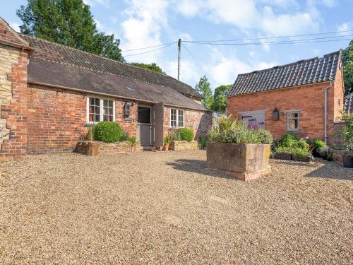 an old brick house with a courtyard in front of it at Croxton Lodge & Curlews Nest in Croxton Kerrial