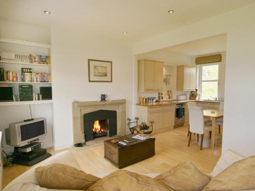 a living room with a fireplace and a kitchen at Tigh Beg in Lerags