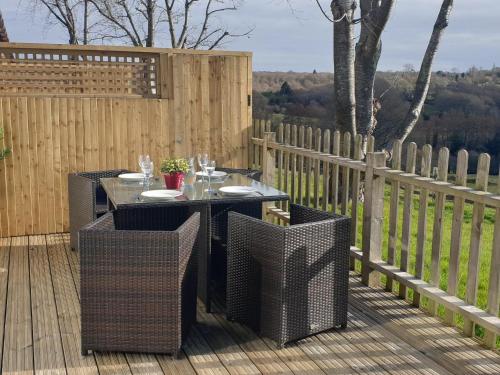 a table and chairs on a deck with a fence at Elm Cottage in Uckfield