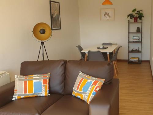 a living room with a brown couch and a table at Elm Cottage in Uckfield