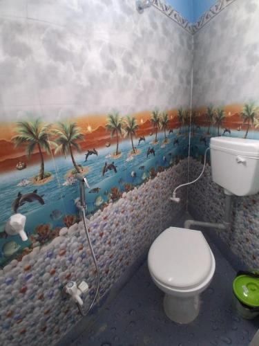 a bathroom with a toilet and a painting on the wall at Bhakta Bhawan in mayapur