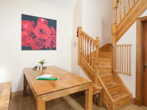 a room with a wooden table and a painting of roses at Rose Cottage - Ukc6257 in Linlithgow
