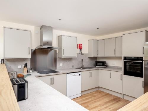 a white kitchen with white cabinets and appliances at Largo Lodge - Ukc5801 in Lundin Links