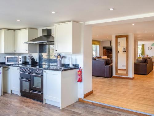 a kitchen with white cabinets and a living room at Nutley Farmhouse in Uckfield