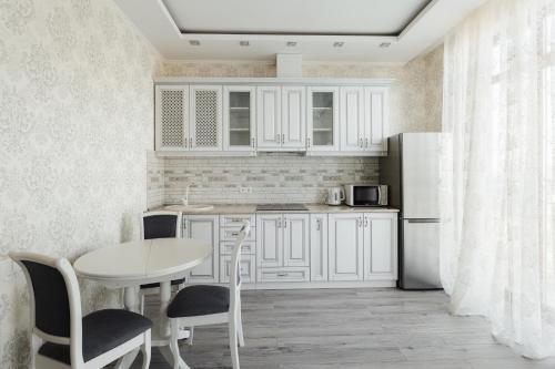 - une cuisine avec des placards blancs, une table et un réfrigérateur dans l'établissement City Center Apartment, à Odessa