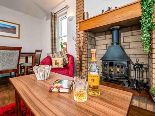 a bottle of wine on a wooden table with a fireplace at Mountain View-Ukc5060 in Aviemore