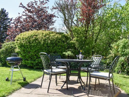 a table and chairs with a grill and a bbq at Acorn Cottage in Ashover