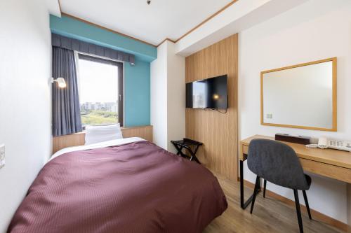 a room with a bed and a desk and a computer at Mito Hotel Season in Mito