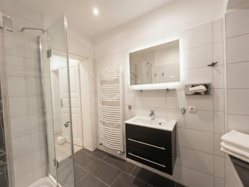 a white bathroom with a sink and a shower at Hof Steinhütten Boutique Apartments in Westerhever
