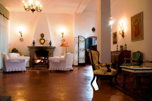 a living room with white chairs and a fireplace at Hotel La Villarosa Terme in Ischia