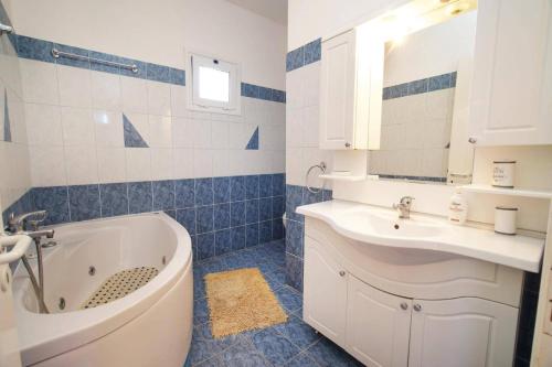a bathroom with a tub and a sink and a mirror at Villa Marina Epavlis by Villa Plus in Karavomylos