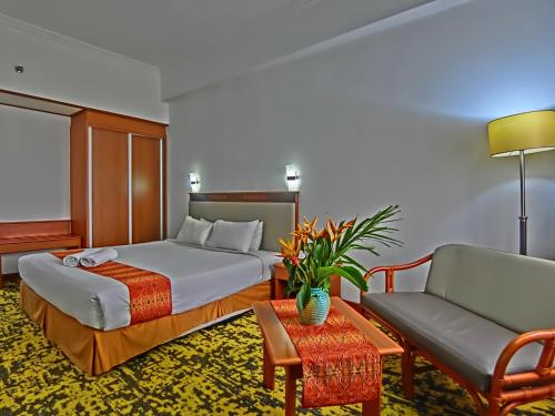 a hotel room with a bed and a couch at Hotel Grand Continental Kuching in Kuching