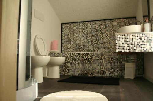 baño con lavabo, aseo y pared de azulejos en The Incantation Guest House, en Montesilvano