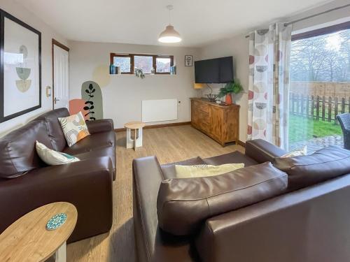 a living room with a leather couch and a table at Cherry Pip in Uckfield