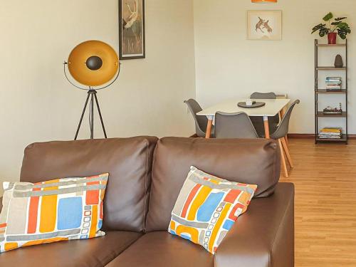 a brown leather couch with pillows in a living room at Birch Cottage in Uckfield