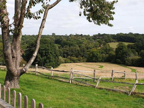 a wooden fence with a tree and a field at Birch Cottage in Uckfield