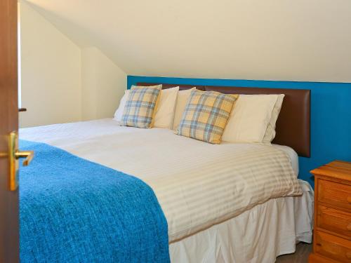 a bedroom with a bed with a blue headboard at Chestnut Cottage in Uckfield