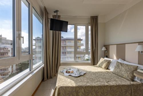 a hotel room with a bed and large windows at Hotel Cristallo in Riccione