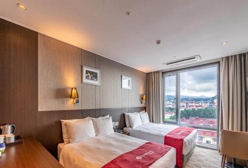 a hotel room with two beds and a window at Ramada by Wyndham Jeju City Hall in Jeju