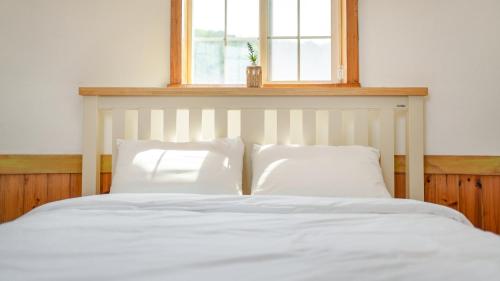 a white bed with two pillows and a window at Daebudo Sketch Pension in Ansan