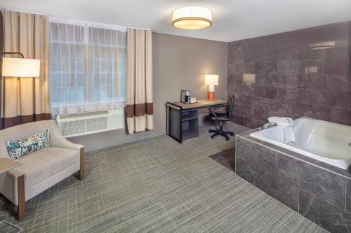 a hotel room with a tub and a chair and a desk at Comfort Inn in Halifax