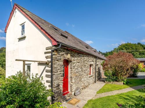 an old stone house with a red door at Honeysuckle - Uk35244 in Llanfyrnach