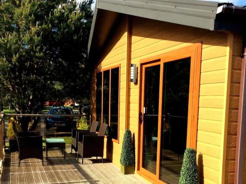a yellow building with a patio with chairs and tables at Serenity Lodge-Uk3456 in Felton