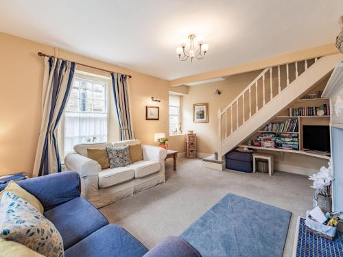a living room with a couch and a staircase at Peaseblossom House in Alnwick