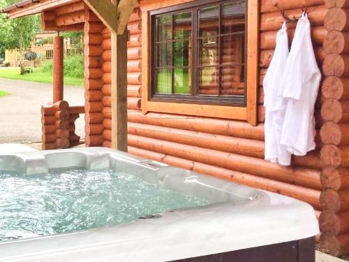 a hot tub in front of a log cabin at Hadrians Lodge - Uk3478 in West Thirston