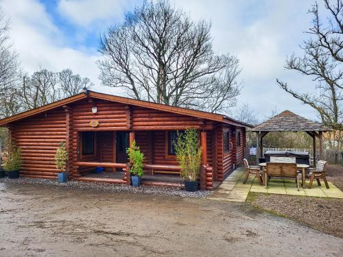 a log cabin with a table and a grill at Tweed Log Cabin-Uk3479 in West Thirston