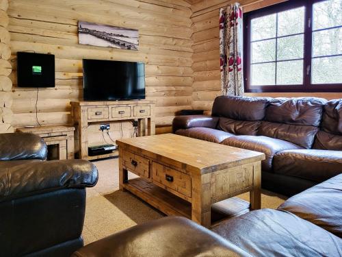 a living room with couches and a tv and a table at Tweed Log Cabin-Uk3479 in West Thirston