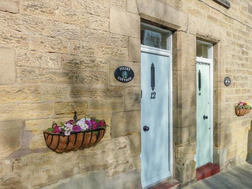 a basket of flowers on the side of a building at Juliet Cottage in Alnwick