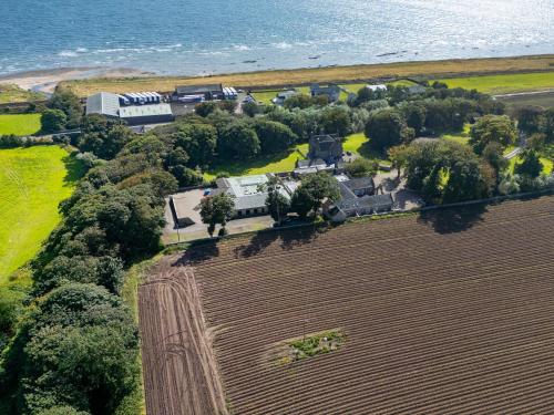 an aerial view of a house in a field next to the ocean at The Courtyard Apartment - Ukc6965 in Panbride