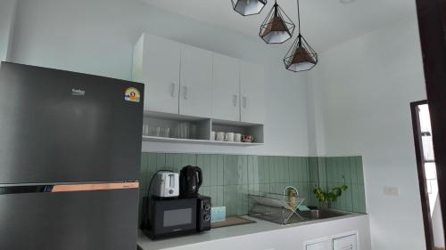 a kitchen with a refrigerator and a microwave at บ้านพักขอนแก่น888 in Ban Non Muang