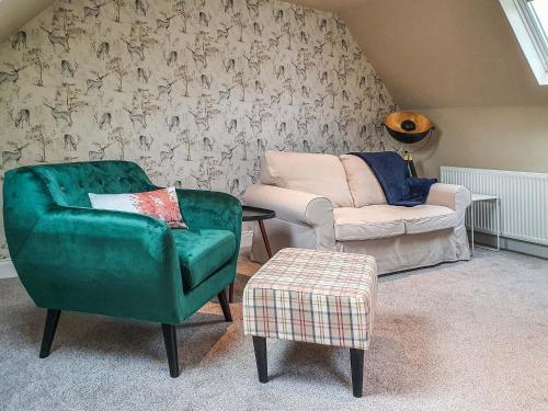 a living room with a green chair and a couch at Oakbank Cottage - Uk7574 in Pitlochry