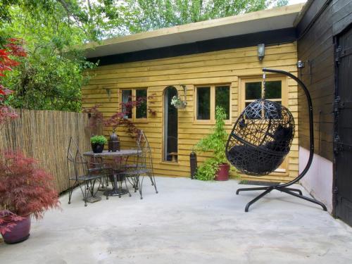 a patio with a table and chairs in front of a house at The Stable At Hilltop Farm in Mottisfont
