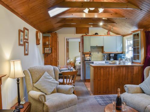 a living room with two chairs and a kitchen at The Stables in Winfrith Newburgh