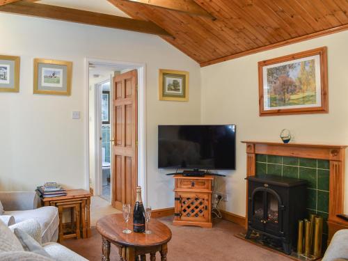 a living room with a fireplace and a flat screen tv at The Stables in Winfrith Newburgh
