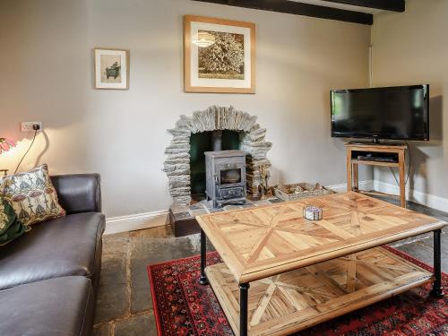 a living room with a wooden coffee table and a fireplace at Jasmine Cottage - Uk35245 in Llanfyrnach
