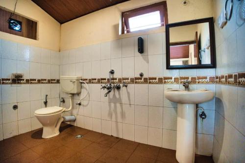 a bathroom with a toilet and a sink and a mirror at Coffee County in Srimangala