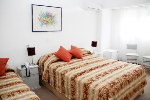 a bedroom with a bed with red pillows on it at Hotel Americana in Punta del Este