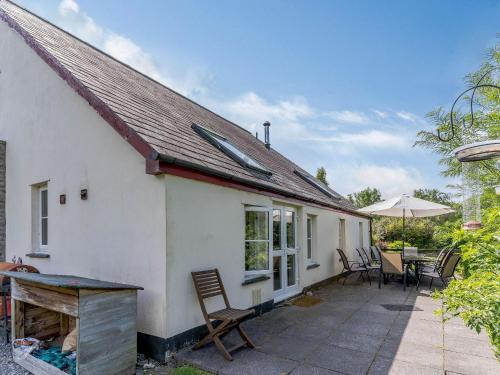 a white cottage with a table and chairs and an umbrella at The Coach House - Uk35246 in Llanfyrnach