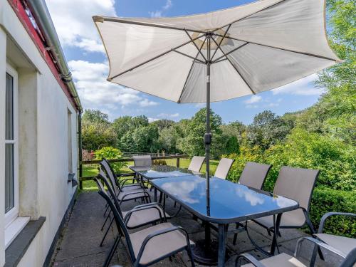 a patio with a table and chairs and an umbrella at The Coach House - Uk35246 in Llanfyrnach