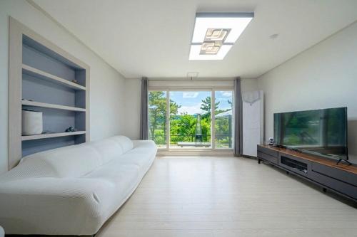 a living room with a white couch and a flat screen tv at Busan Mandiga Pool Villa in Busan