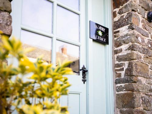 a door with a sign on it next to a brick building at Jasmine Cottage - Ukc4694 in Kilkhampton