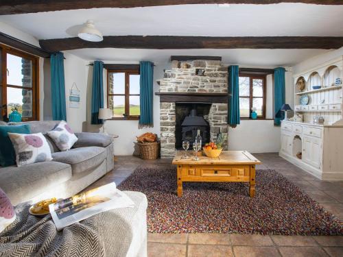 a living room with a couch and a fireplace at Jasmine Cottage - Ukc4694 in Kilkhampton