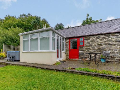 a small cottage with a red door and a table at Ivy Cottage - Uk35243 in Llanfyrnach