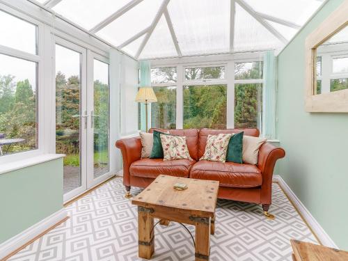 a living room with a leather couch and windows at Ivy Cottage - Uk35243 in Llanfyrnach