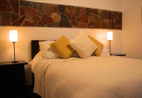 a bedroom with a bed with two lamps on it at Posada El Capullo in Colonia del Sacramento