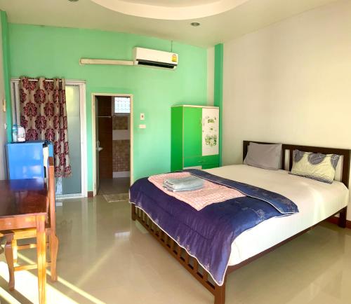 a bedroom with a bed and a green wall at สายป่านอาพาร์ทเม้นท์ in Ban Bung Sam Phan Nok